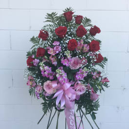 Standing floral spray of red and pink roses with a pink ribbon