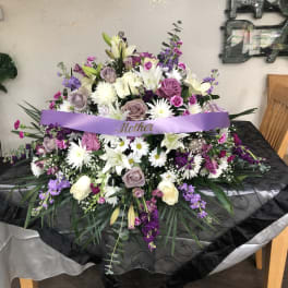 Large purple and white floral arrangement with a ribbon reading Mother