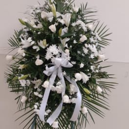 White funeral wreath on a stand with a white ribbon