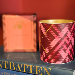 Patterned candle tin on stacked books with a blurred box behind it