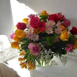 Mixed bouquet of roses, alstroemeria, and filler flowers in a glass vase