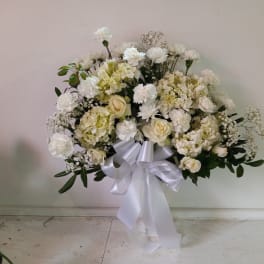 White floral standing spray with a large white ribbon bow