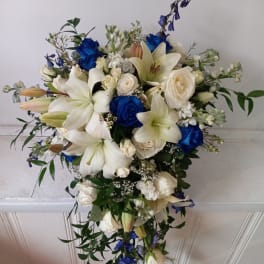 Cascade bouquet of white lilies, roses, and blue flowers