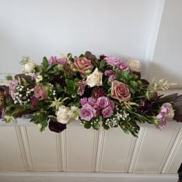 Low floral arrangement with pink and cream roses on a white surface