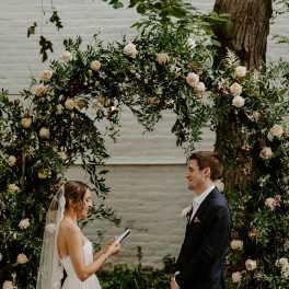 Bride and groom standing beneath a floral wedding arch