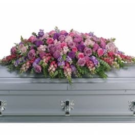Pink and purple floral casket spray on a gray casket