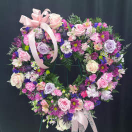 Heart-shaped floral wreath with pink and purple flowers and a ribbon bow
