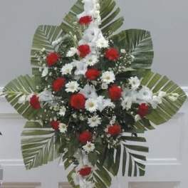Standing floral spray with red and white flowers and large palm leaves