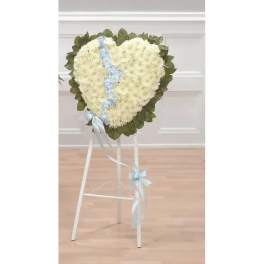 Heart-shaped white floral wreath on a stand with a blue ribbon