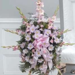 Standing floral spray with pink and lavender flowers on a white easel