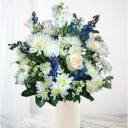 White and blue flowers arranged in a tall white vase