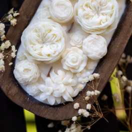 White floral arrangement in a wooden oval tray with small filler flowers