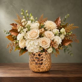 Cream and peach floral arrangement in a textured amber vase