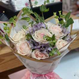 Bouquet of pale pink roses and purple flowers wrapped in paper