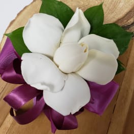 White flower petals with green leaves and a purple ribbon on wood