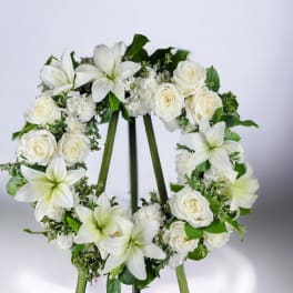 White floral wreath with roses and lilies on a stand