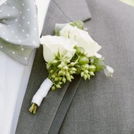 White rose boutonniere pinned to a gray suit jacket