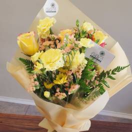 Bouquet of yellow roses and mixed blooms wrapped in cream paper