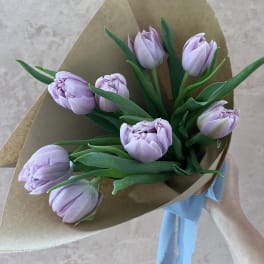 Bouquet of pale lavender tulips wrapped in brown paper with a blue ribbon