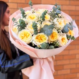 Bouquet of pale yellow roses wrapped in pink paper