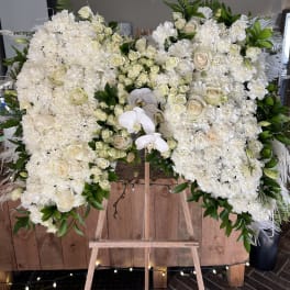 Large white floral spray on an easel with roses and orchids