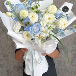 Blue and white bouquet with roses, daisies, and pom flowers in white wrap