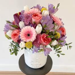 Pink, purple, and white bouquet in a white ceramic vase
