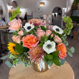 Mixed bouquet of peach and pink flowers in a gold vase