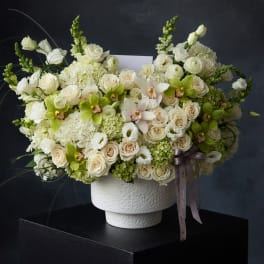 Large white and cream floral arrangement in a textured white vase