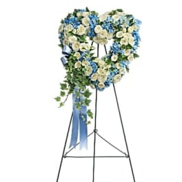 Heart-shaped floral wreath on a standing easel with blue and white flowers