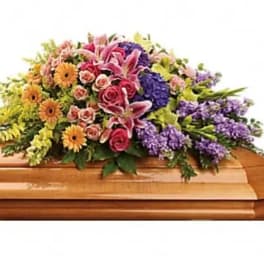 Colorful floral spray on a casket with pink, purple, and yellow blooms