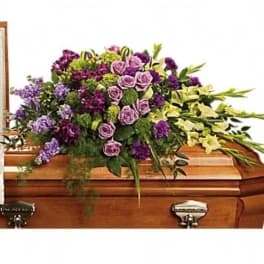 Purple and green floral spray on a wooden casket