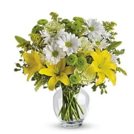 Yellow lilies and white daisies in a clear glass vase