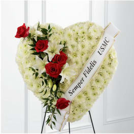 Heart-shaped funeral wreath with red roses and white lilies on a stand