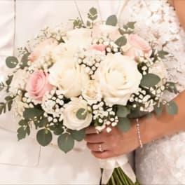White and blush rose bouquet with eucalyptus held by a bride and groom