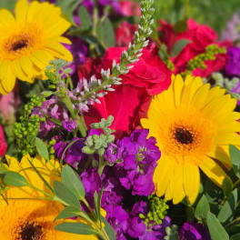 Bright mixed bouquet with yellow gerbera daisies, red roses, and purple flowers