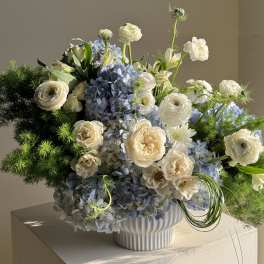 Blue hydrangea and white flower arrangement in a white vase