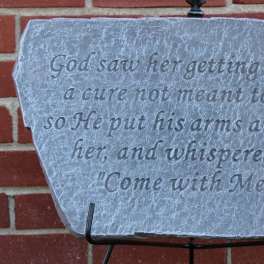 Engraved stone plaque with a religious quote on a metal stand