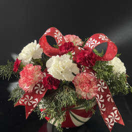 Holiday floral arrangement with red and white carnations in a candy cane vase