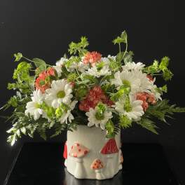 White daisies and pink carnations in a mushroom-decorated ceramic pot