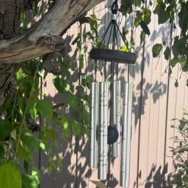 Silver wind chime hanging among tree branches