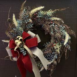 Rustic wreath with berries, pinecones, and a red ribbon bow