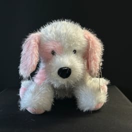 Small plush dog with white and pink fur on a dark surface