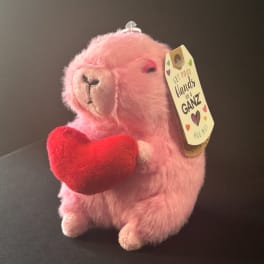 Pink plush alpaca holding a red heart with a hanging gift tag