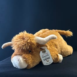 Plush brown-and-white cow toy with a hanging tag