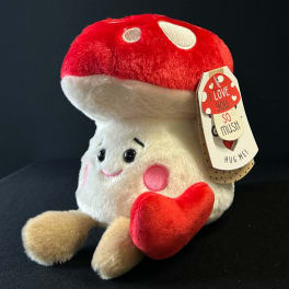 Plush mushroom toy holding a red heart with a hanging love tag