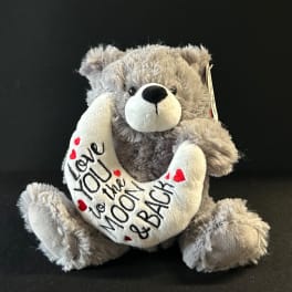 Gray teddy bear holding a heart-shaped pillow with "Love you to the moon & back" text