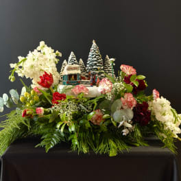 Holiday floral arrangement with white blooms and a miniature winter village centerpiece