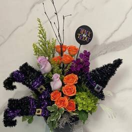 Halloween arrangement with orange and purple roses in a black container