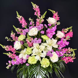 Pink and white floral arrangement with lilies, roses, and snapdragons